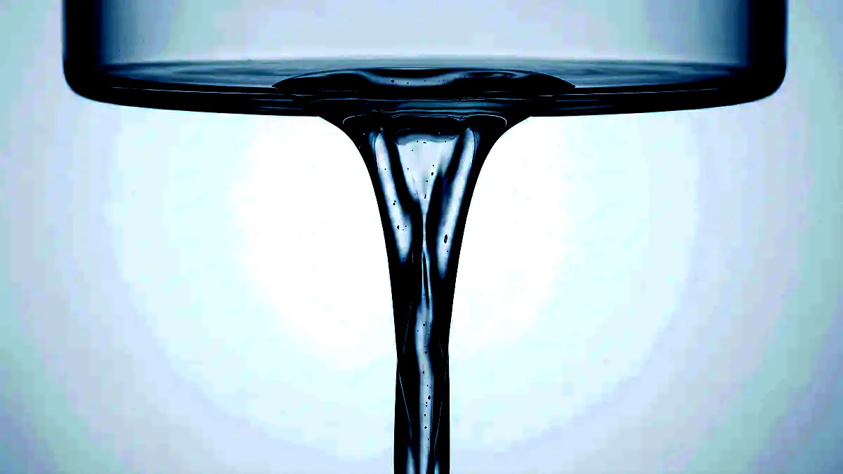 A viscous thread of clear serum drawing down from a glass surface.
