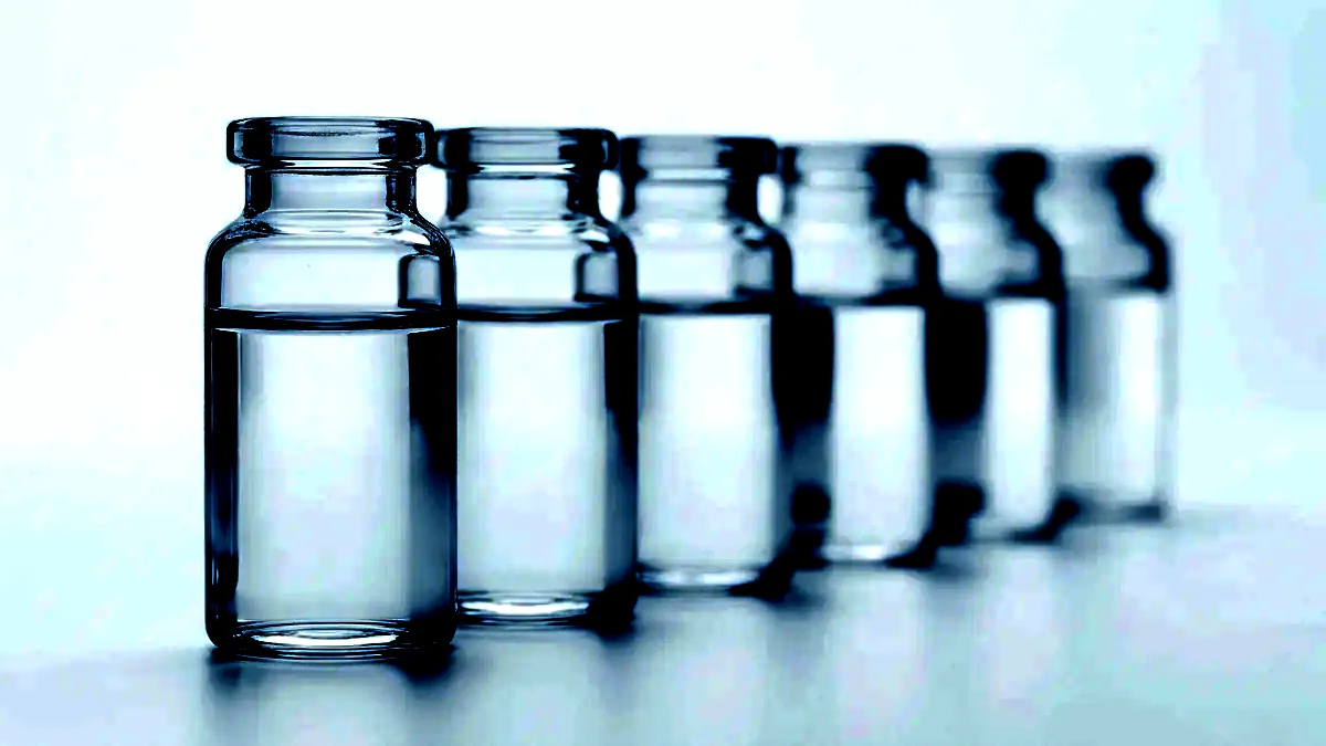 A row of plain unlabelled glass vials receding into shallow focus on a white surface.