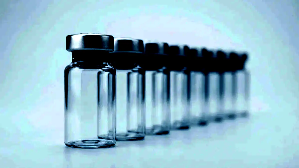 A row of unlabelled glass vials with grey stoppers and crimp seals on a white surface.