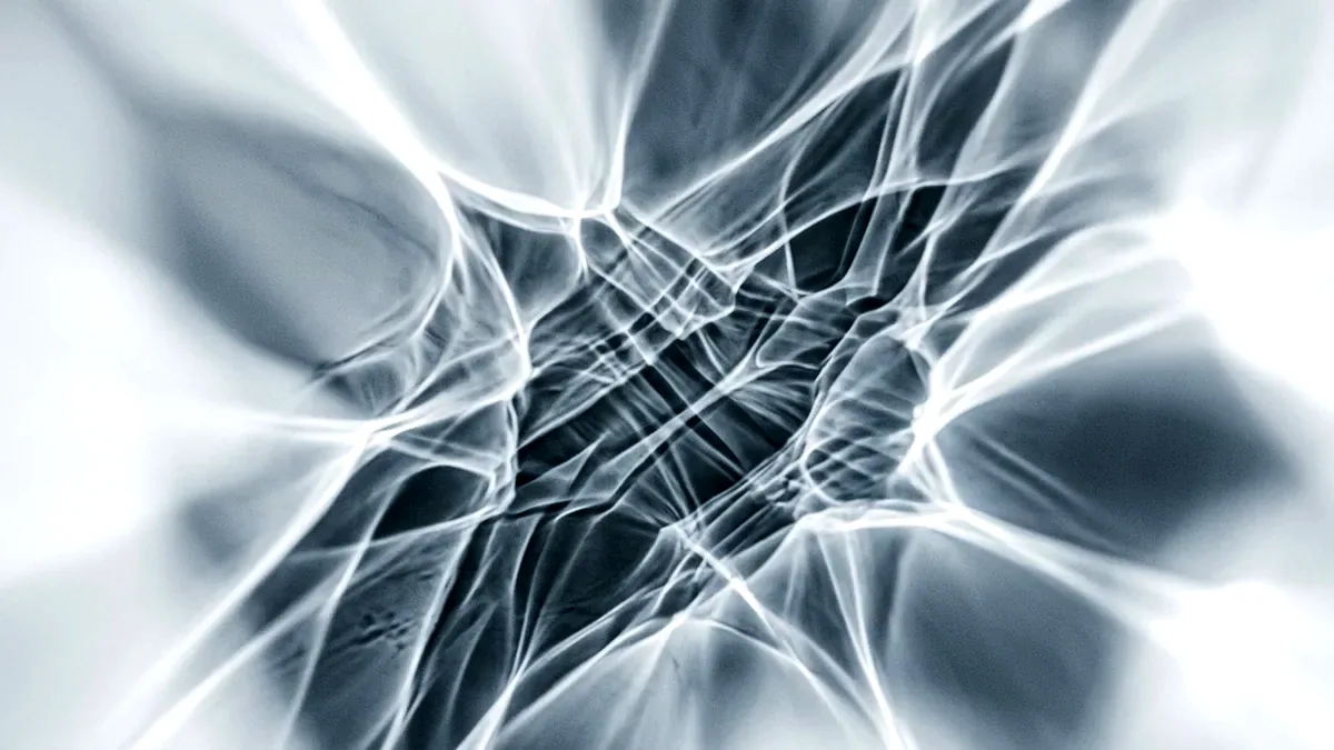 Caustic light patterns cast across a white surface by a crystal prism out of frame.