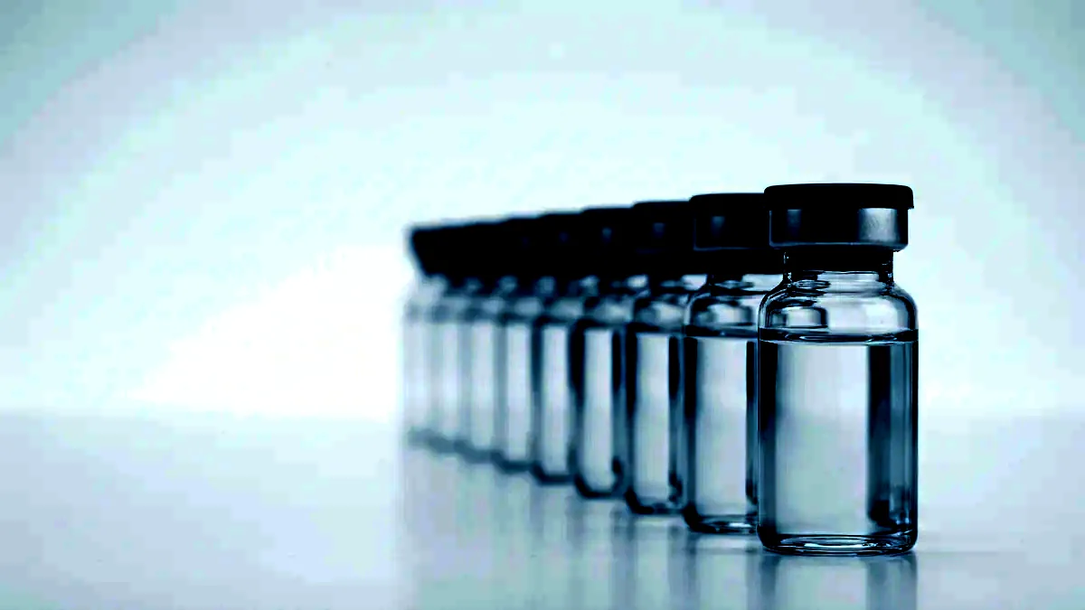 A row of unlabelled glass vials with grey stoppers and crimp seals on a white surface.
