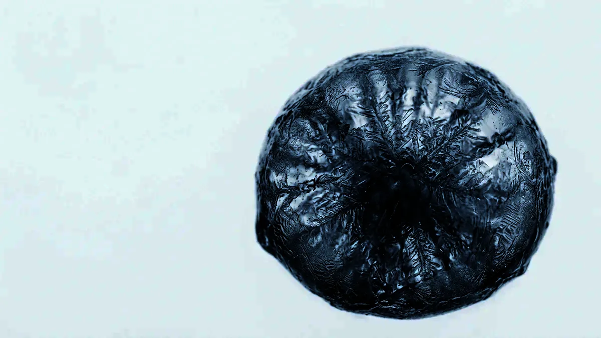 Extreme close-up of a frozen droplet clouded with fine internal crystal structure.