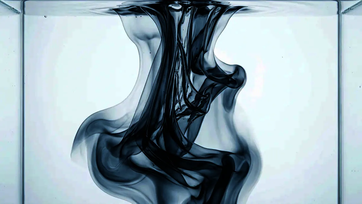 Ribbons of denser clear fluid sinking and folding through water.